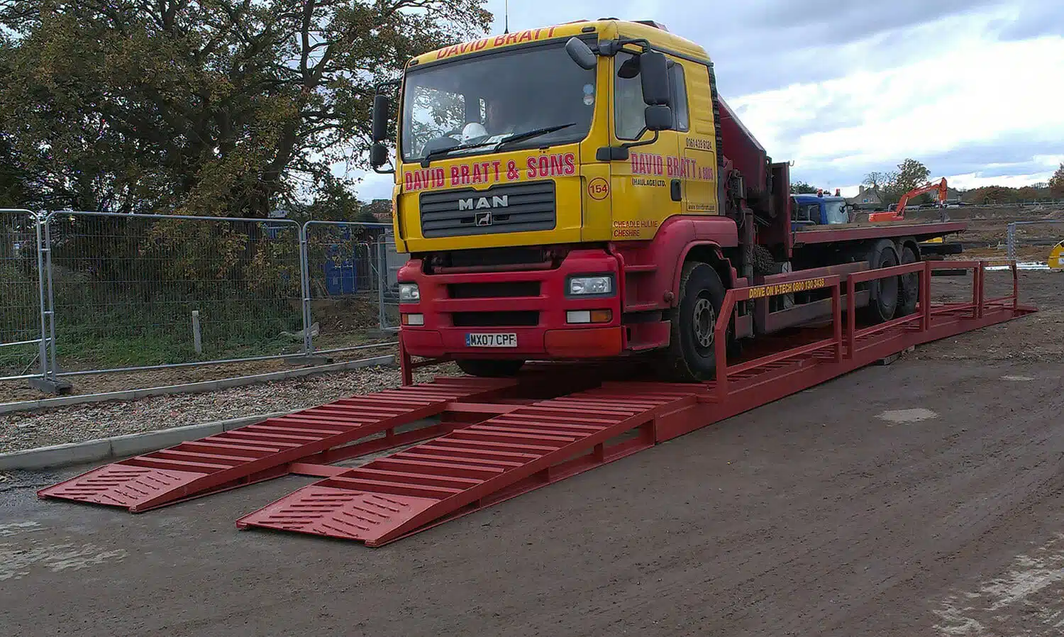 A David Bratt & Sons truck driving over the DriveOn V-Tech waterless wheel cleaning system on a construction site.
